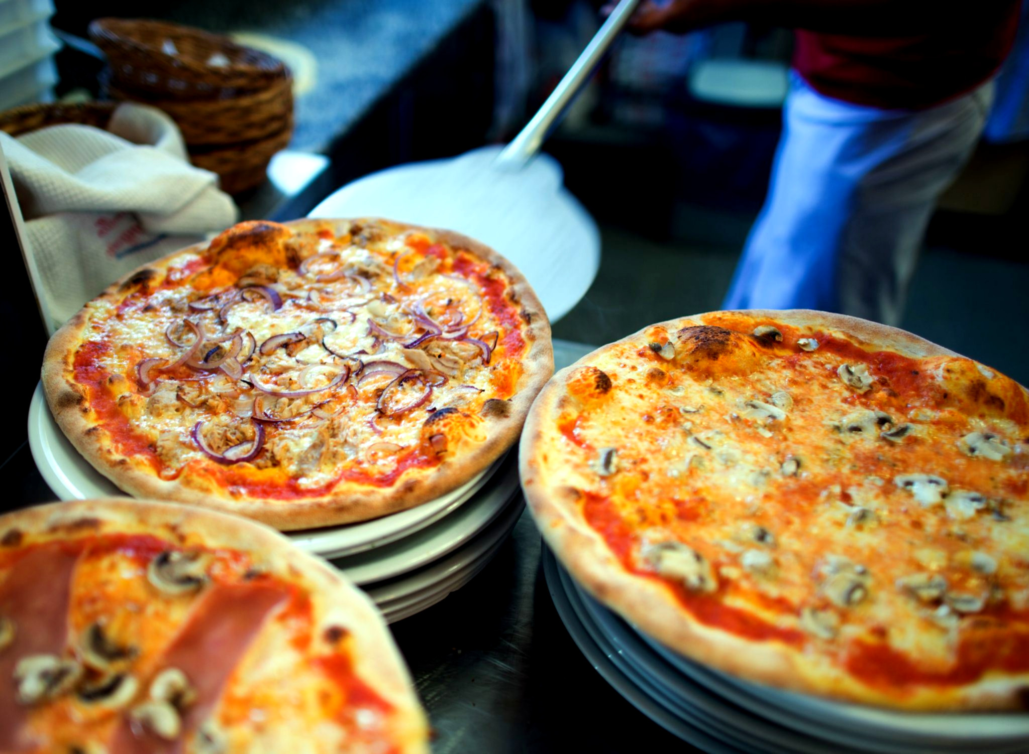 Bunte Pizzastücke auf Holztisch angerichtet.