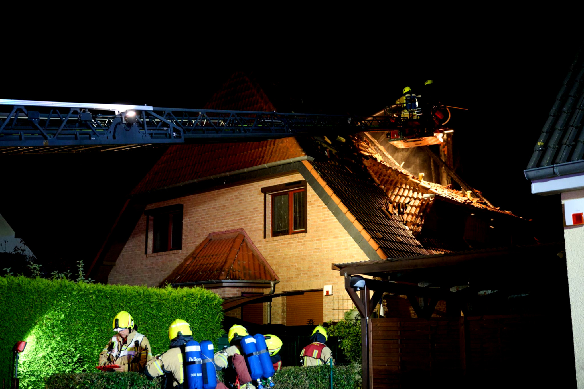 Flammen lodern, Rettungskräfte versorgen Verletzten.